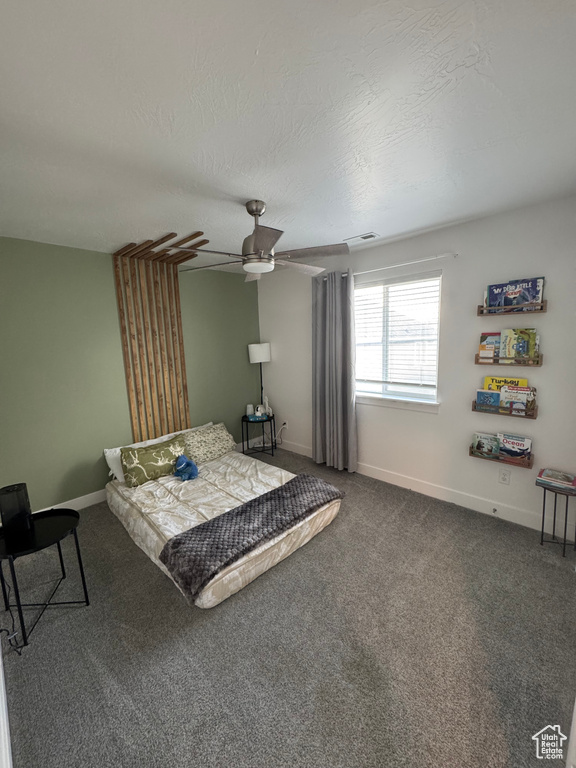 Bedroom featuring a textured ceiling, a ceiling fan, visible vents, baseboards, and dark colored carpet