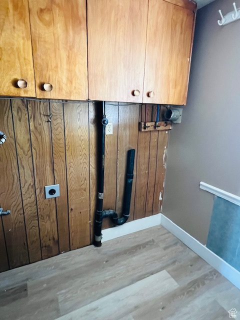 Laundry area with electric dryer hookup, wood finished floors, cabinet space, and baseboards