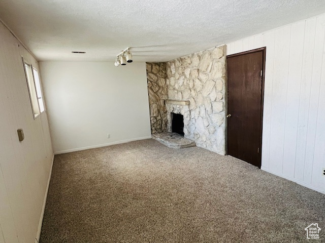Unfurnished living room featuring carpet flooring, a fireplace, and a textured ceiling