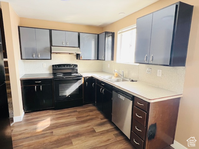Kitchen featuring black electric range, light countertops, a sink, dishwasher, and under cabinet range hood