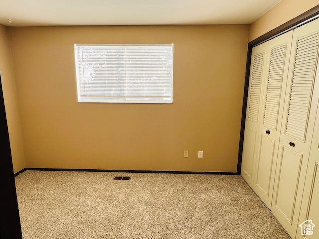 Unfurnished bedroom with a closet, visible vents, light carpet, and baseboards