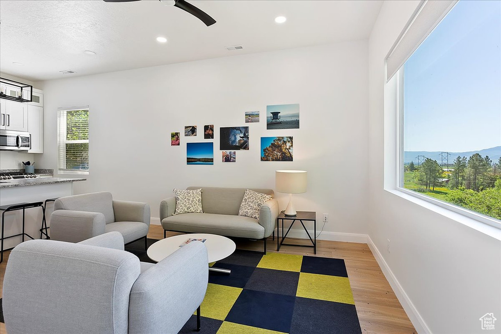 Living area featuring light wood finished floors, ceiling fan, baseboards, and recessed lighting