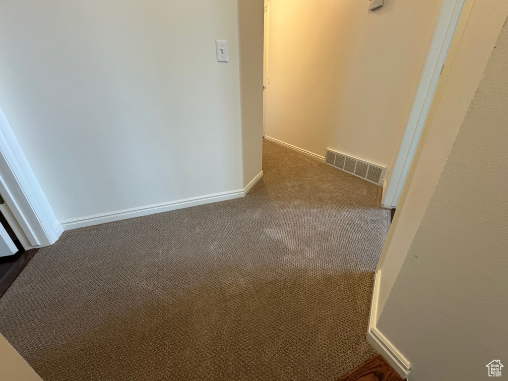 Corridor featuring dark colored carpet and baseboards