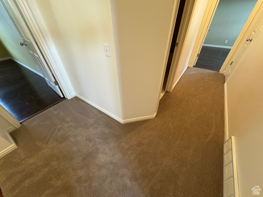 Hall featuring dark carpet and baseboards