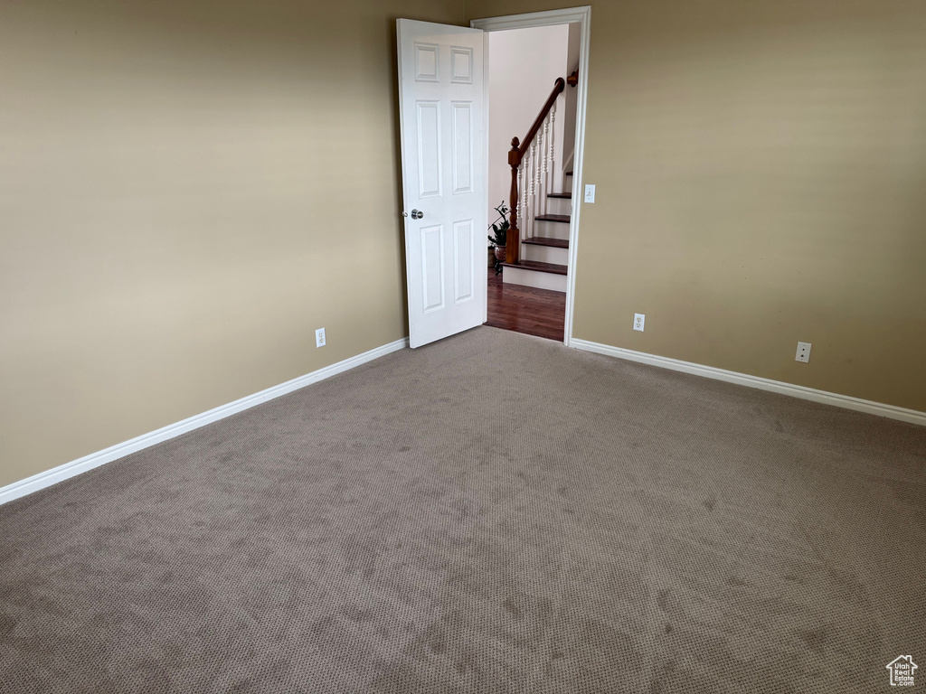 Spare room with baseboards, carpet flooring, and stairway