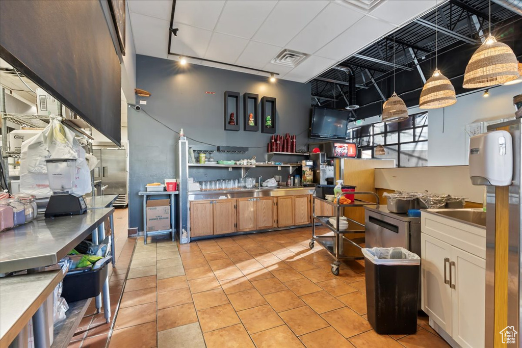 Kitchen featuring light tile patterned floors, light brown cabinets, and visible vents