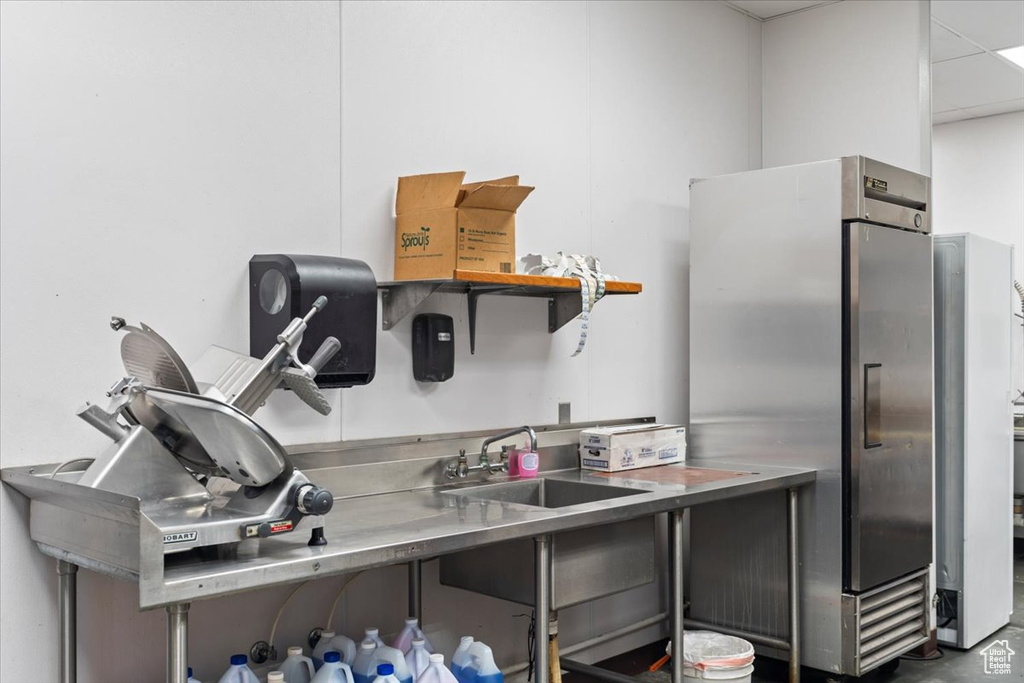 Kitchen featuring freestanding refrigerator, stainless steel countertops, and a sink