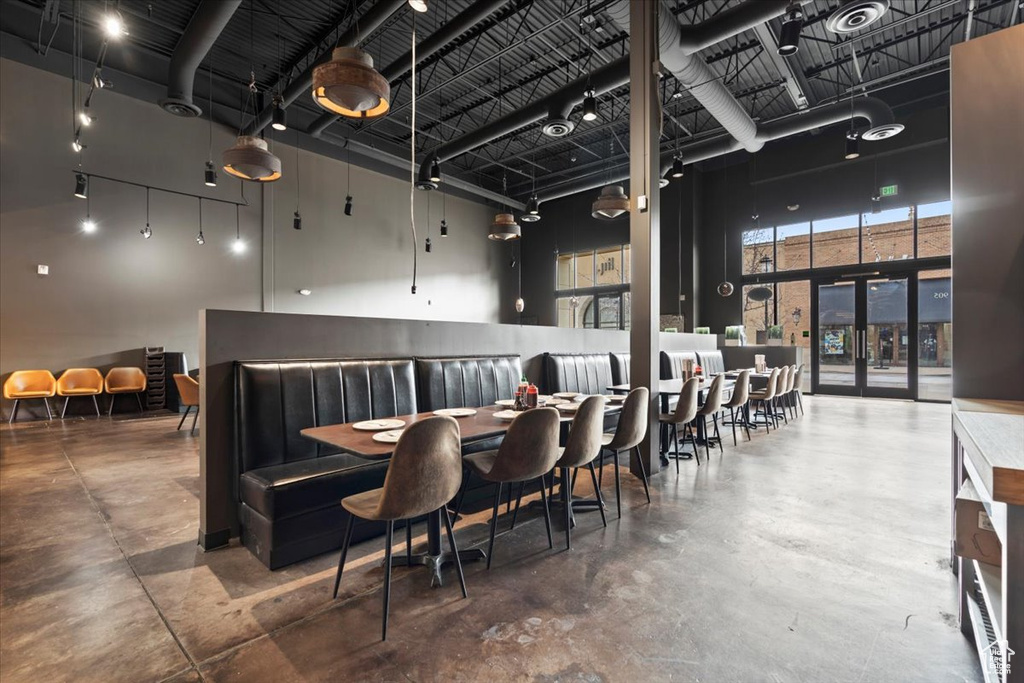 Dining area with a high ceiling, finished concrete floors, and french doors