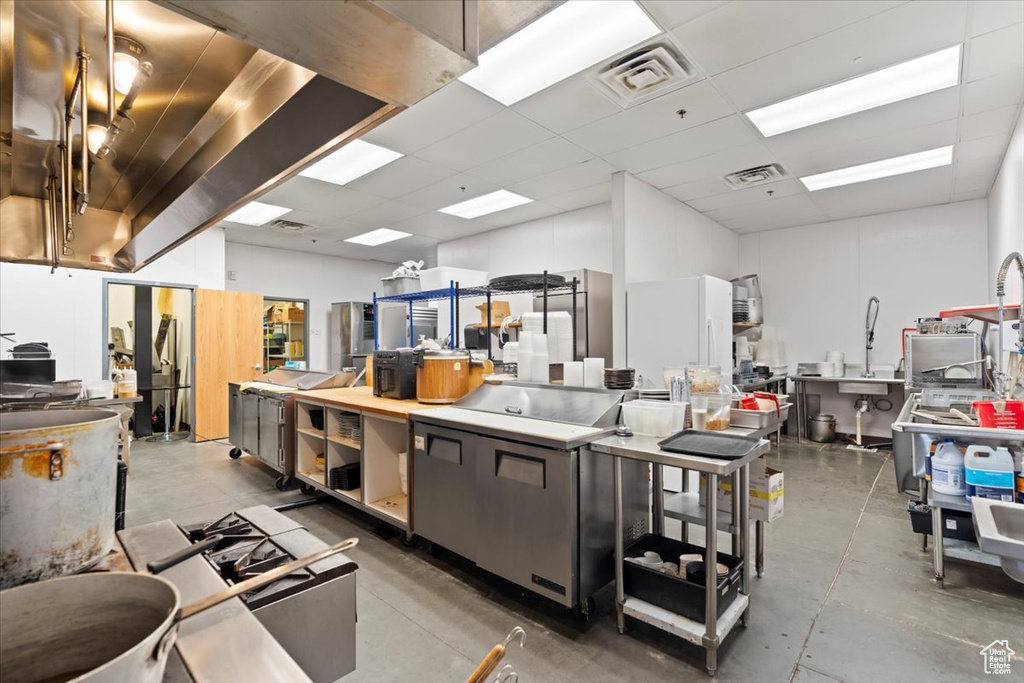 Kitchen featuring a kitchen island, a paneled ceiling, light countertops, and concrete floors