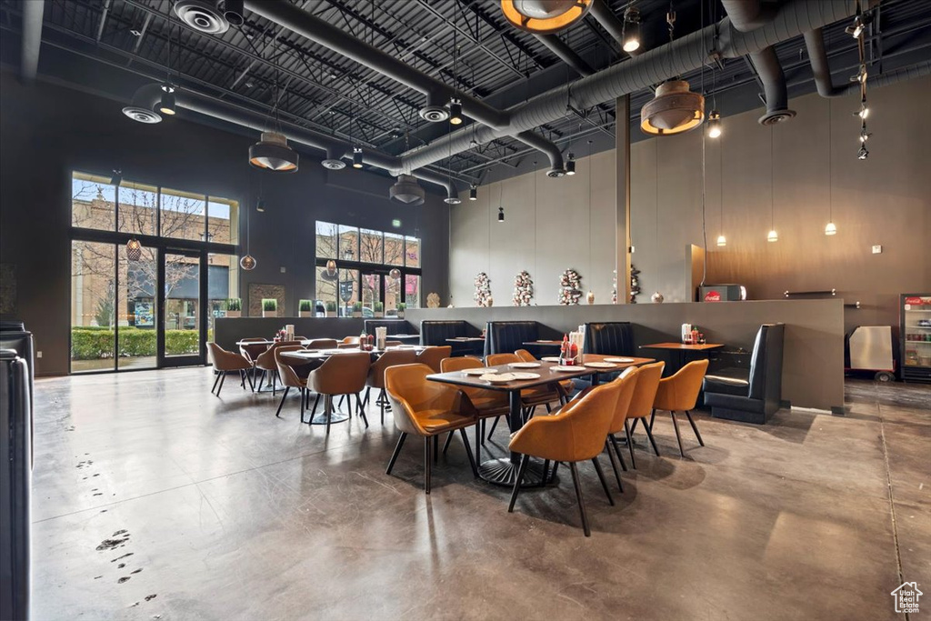 Dining space featuring concrete flooring and a towering ceiling