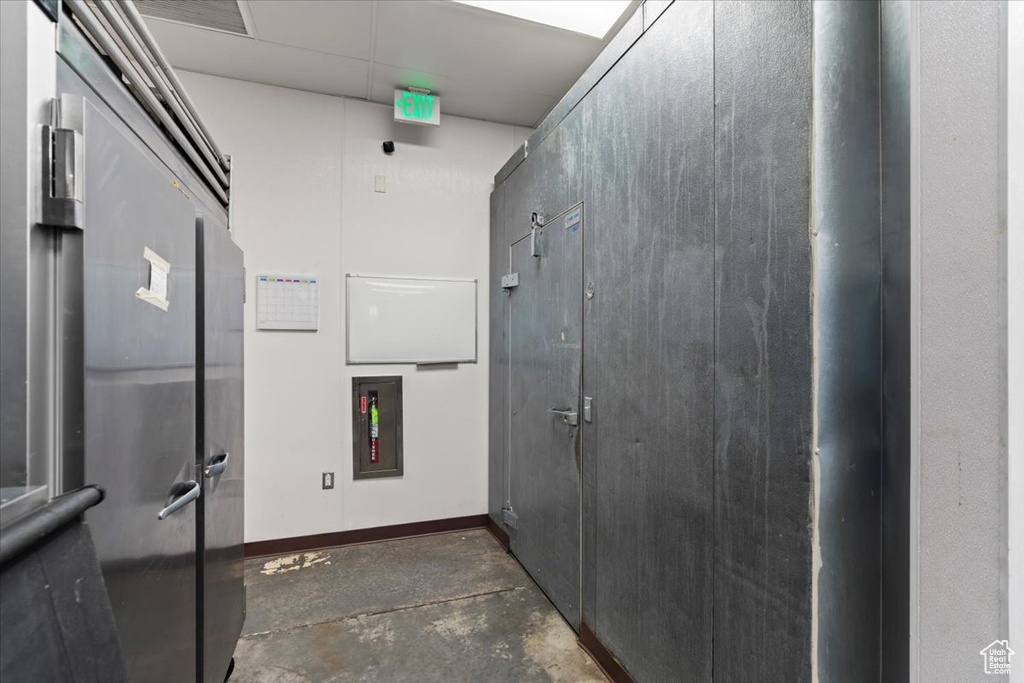 Interior space with baseboards, a drop ceiling, and unfinished concrete flooring