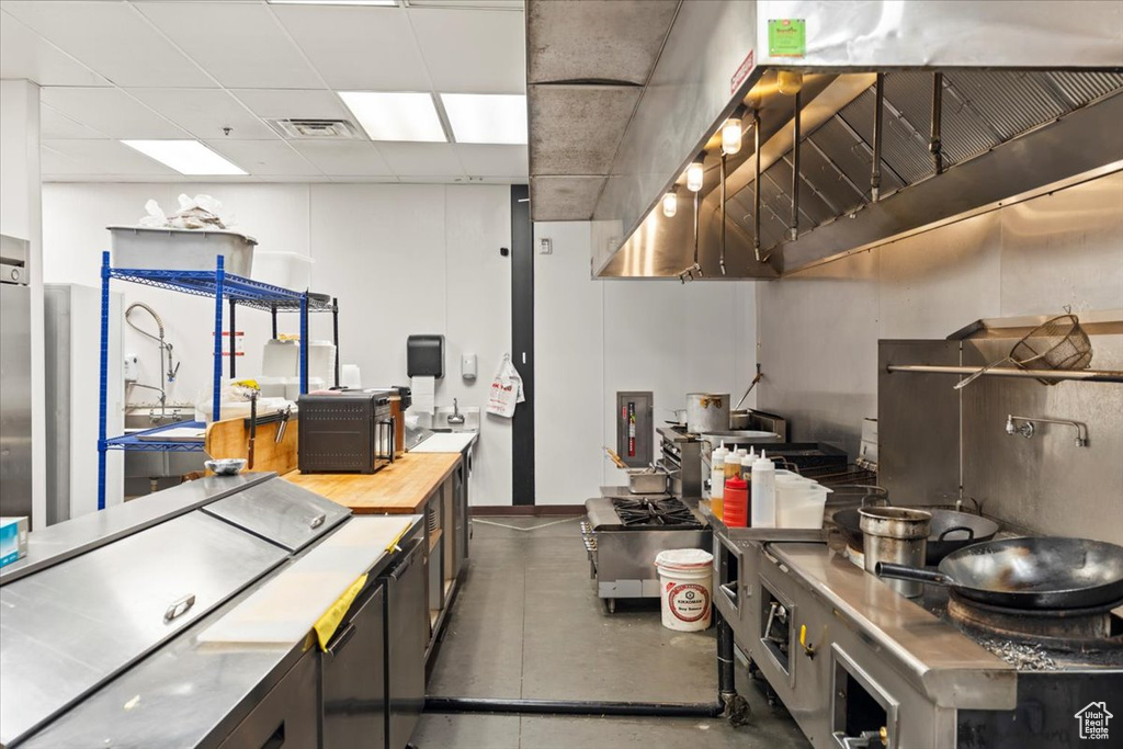 Kitchen with a paneled ceiling, stainless steel countertops, visible vents, and concrete floors