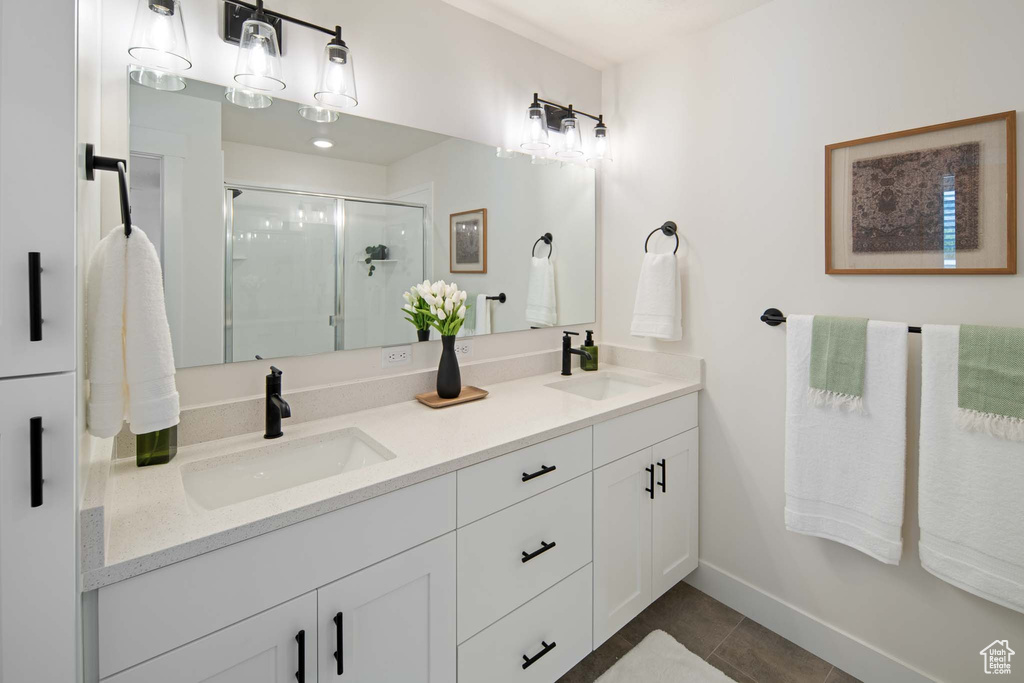Bathroom with a shower stall, double vanity, a sink, and tile patterned floors