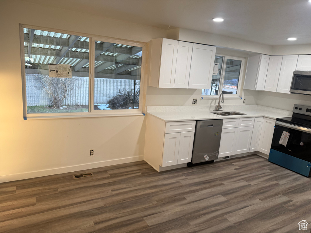 Kitchen featuring light countertops, appliances with stainless steel finishes, a sink, and white cabinets