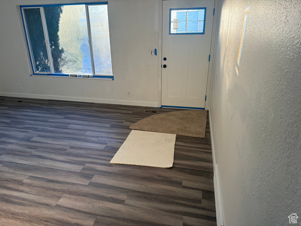 Foyer entrance with baseboards, dark wood-style flooring, and a textured wall