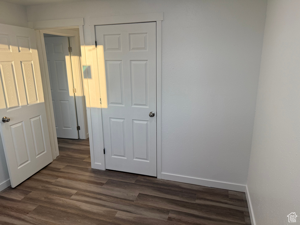Unfurnished bedroom with dark wood-style flooring and baseboards