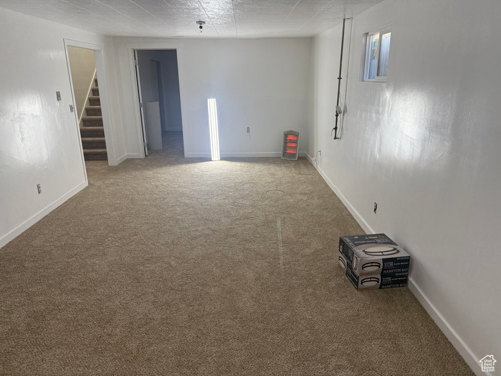 Carpeted spare room featuring stairs and baseboards