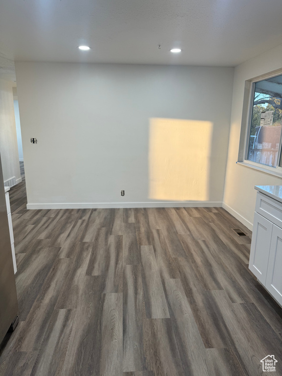 Empty room with baseboards, visible vents, dark wood-style flooring, and recessed lighting
