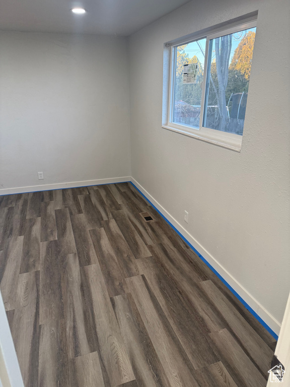 Spare room featuring dark wood-type flooring, recessed lighting, visible vents, and baseboards