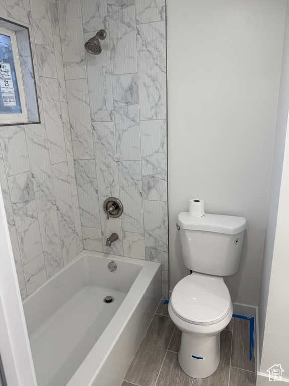 Bathroom with tub / shower combination, toilet, and baseboards