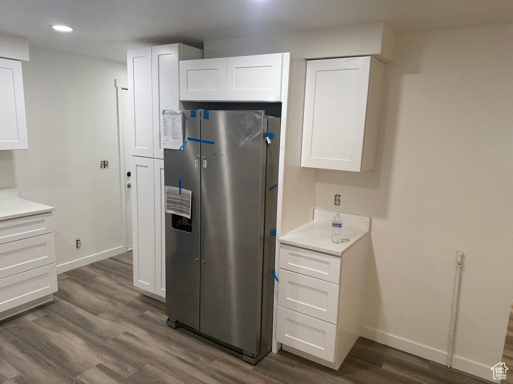 Kitchen featuring baseboards, white cabinetry, dark wood-type flooring, and freestanding refrigerator