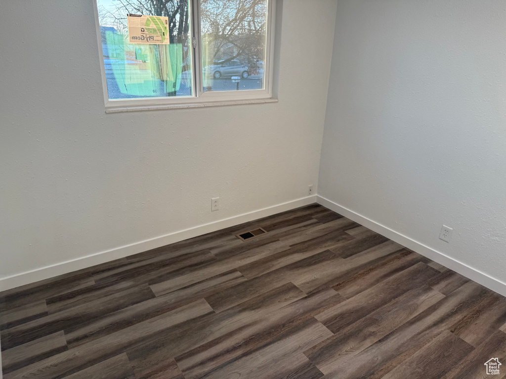 Spare room featuring dark wood finished floors and baseboards