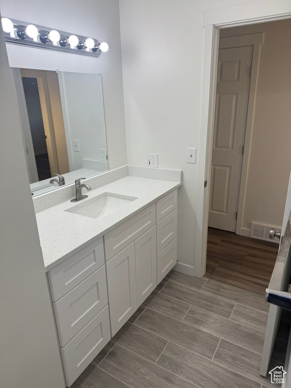 Bathroom featuring baseboards, vanity, visible vents, and wood finish floors