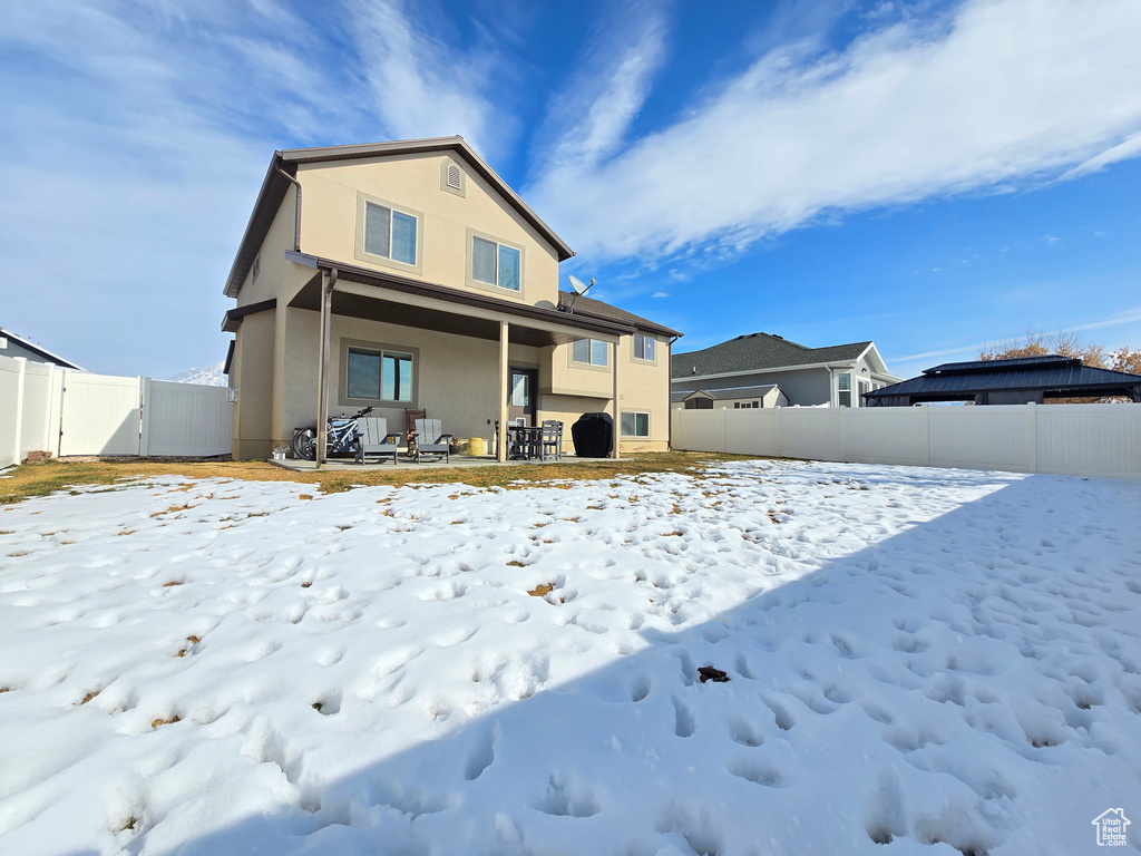 Snow covered rear of property with a fenced backyard and stucco siding