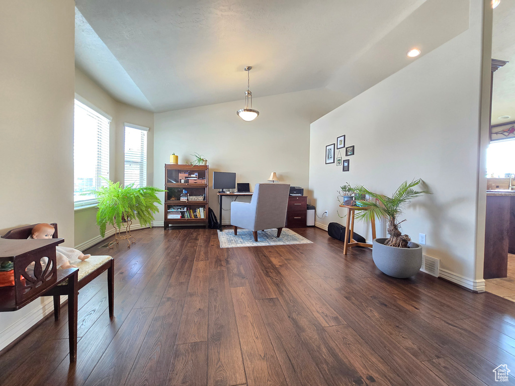 Home office with lofted ceiling, dark wood-type flooring, visible vents, and baseboards