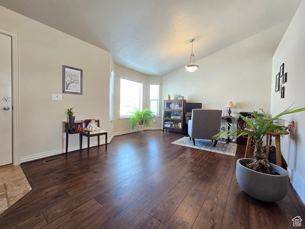 Home office featuring baseboards, visible vents, vaulted ceiling, and dark wood-type flooring