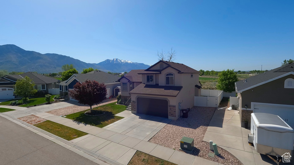 View of front of property featuring concrete driveway, a residential view, stucco siding, a mountain view, and an attached garage
