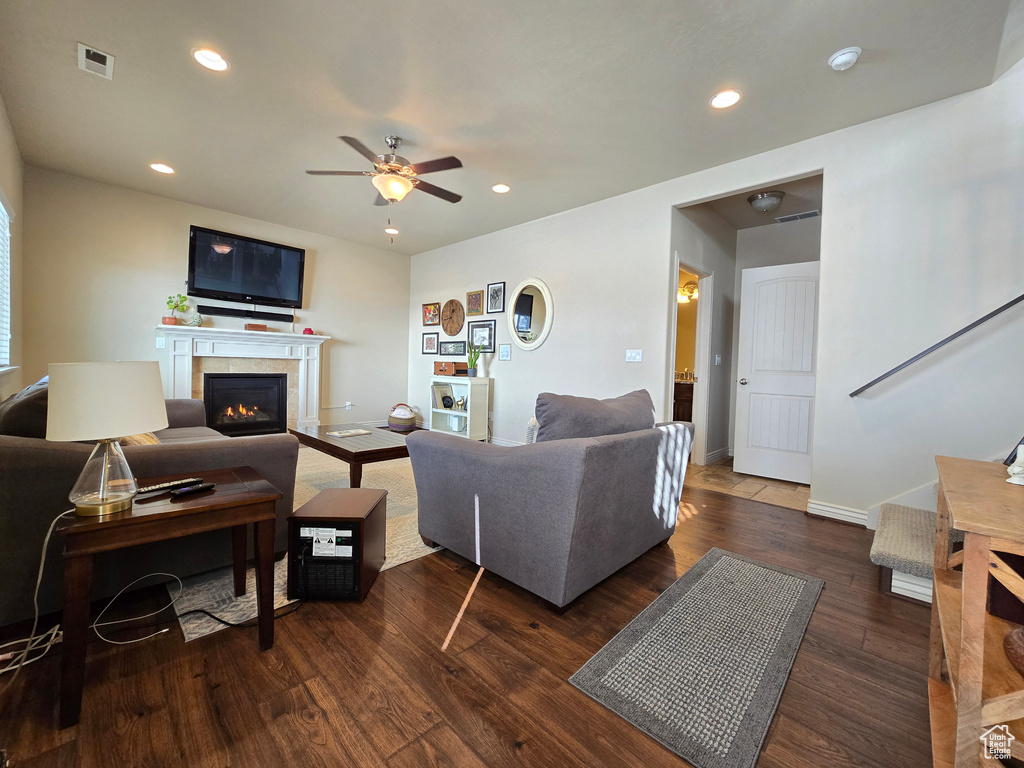 Living room featuring a warm lit fireplace, baseboards, visible vents, dark wood-style flooring, and recessed lighting