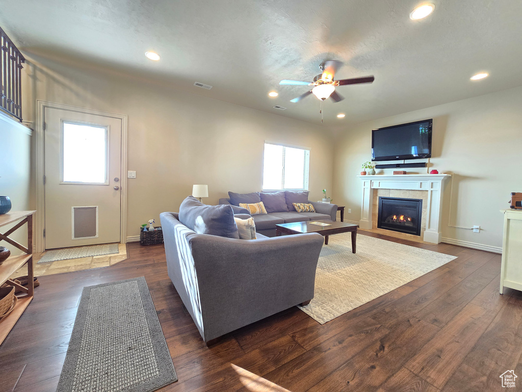 Living area with a tiled fireplace, dark wood finished floors, visible vents, and recessed lighting