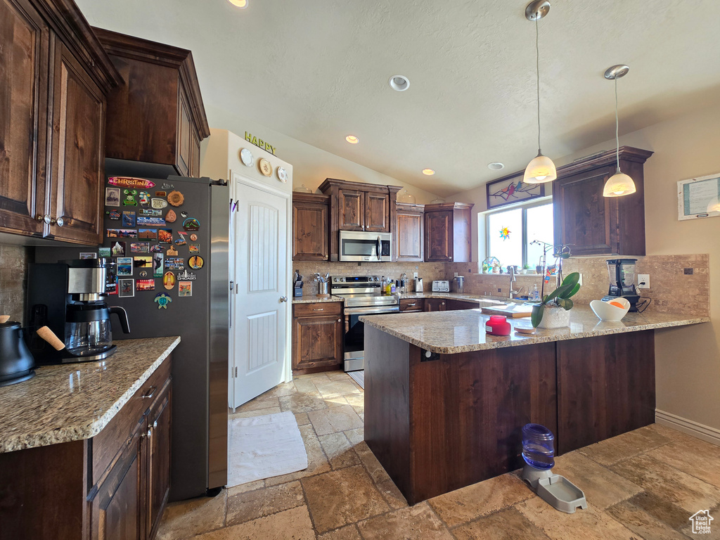 Kitchen featuring hanging light fixtures, stone tile floors, a peninsula, and stainless steel appliances