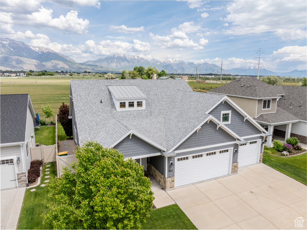 View of front of property featuring stone siding, a mountain view, roof with shingles, and an attached garage