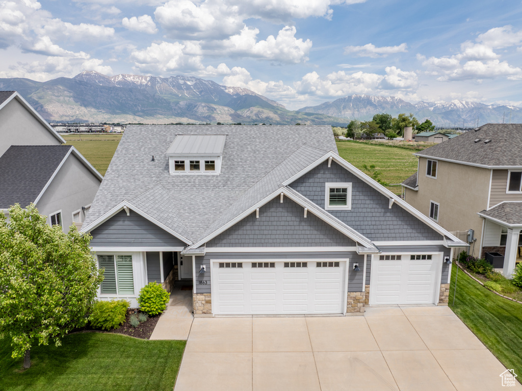 Craftsman-style home featuring a mountain view, stone siding, concrete driveway, and a garage