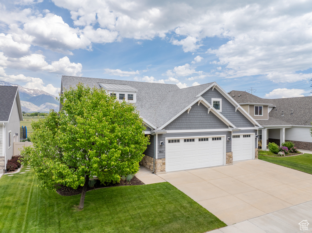 View of front of house with stone siding, concrete driveway, a garage, a front yard, and a shingled roof