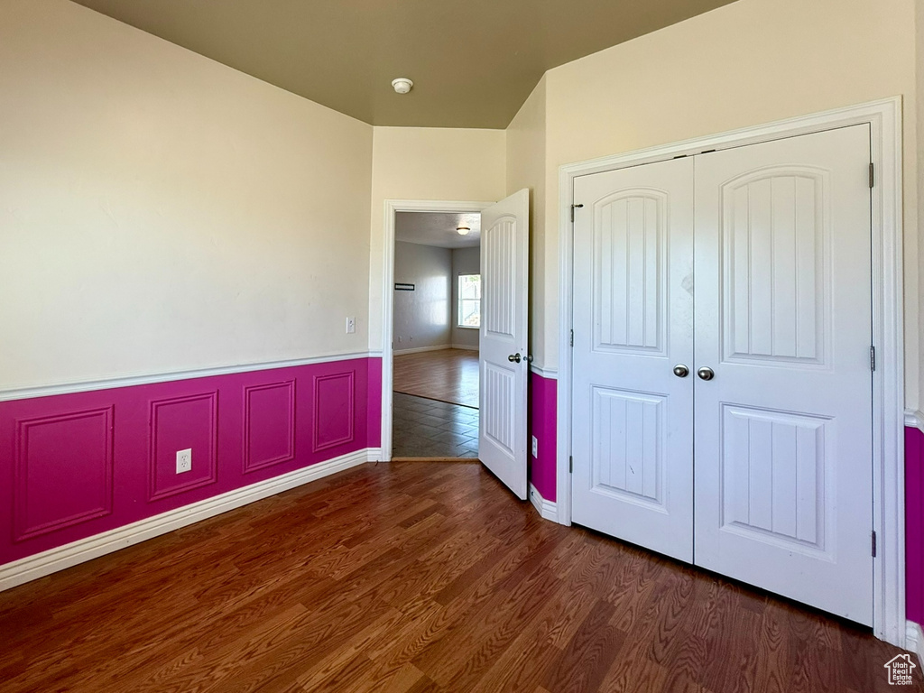 Unfurnished bedroom with a closet, wood finished floors, and wainscoting
