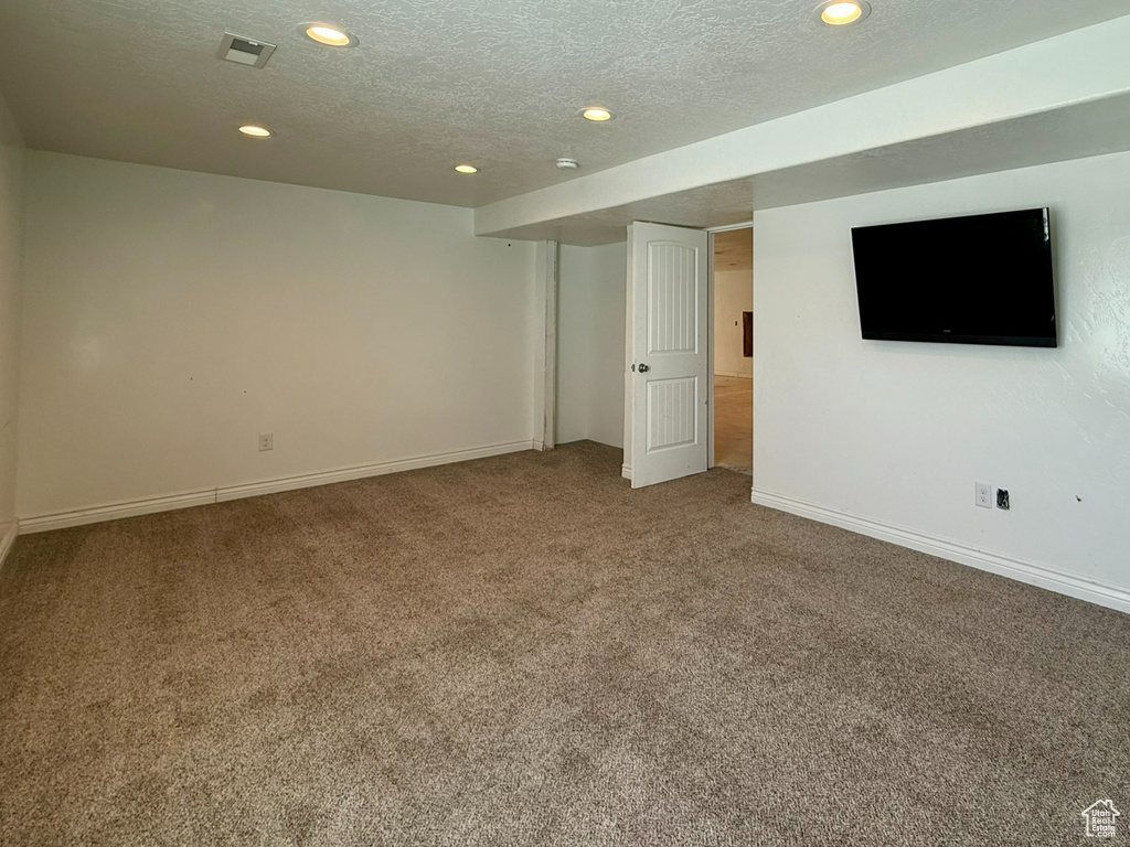 Finished below grade area with carpet floors, recessed lighting, baseboards, and a textured ceiling