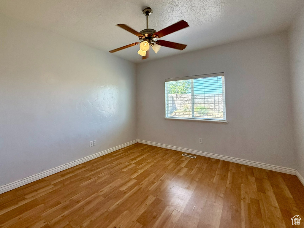 Empty room featuring baseboards, light wood-type flooring, and a ceiling fan