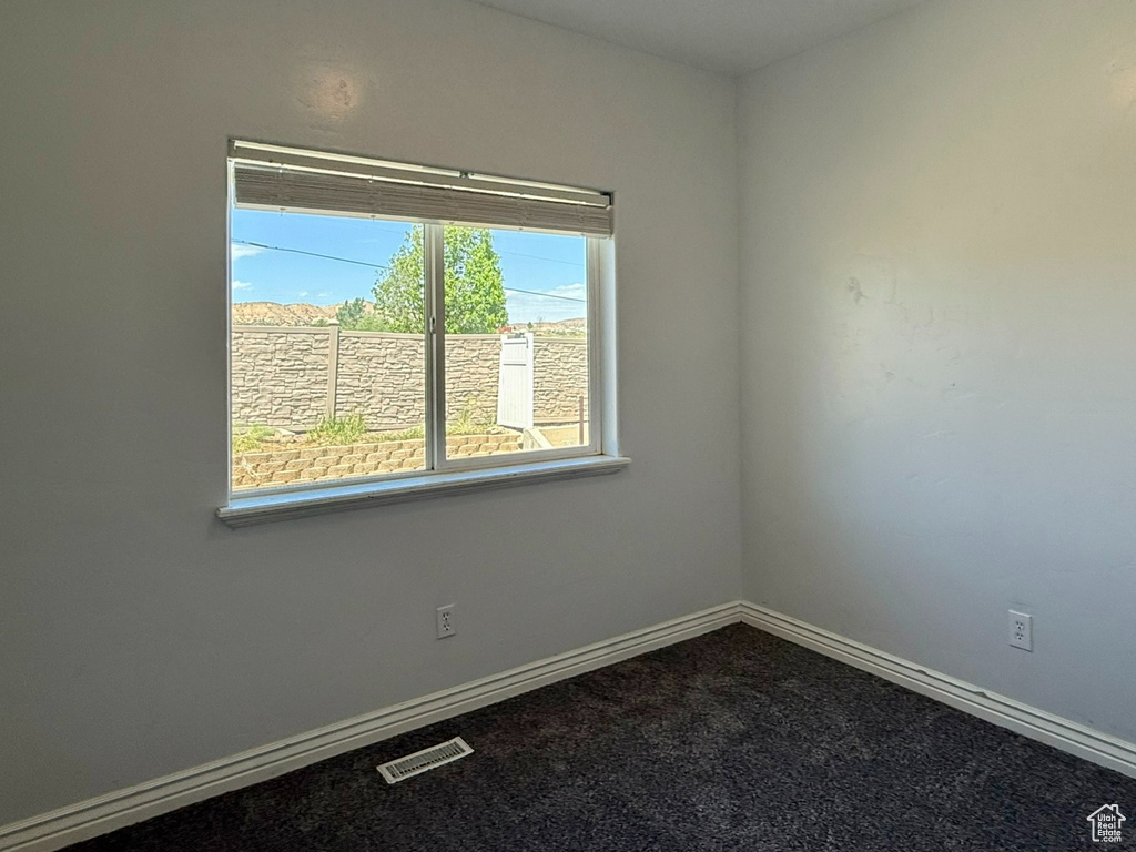Spare room featuring baseboards and dark carpet