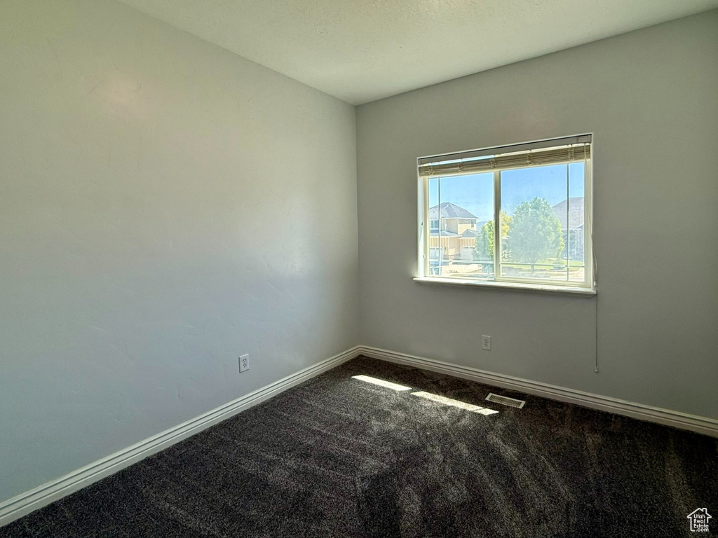 Empty room featuring dark carpet and baseboards