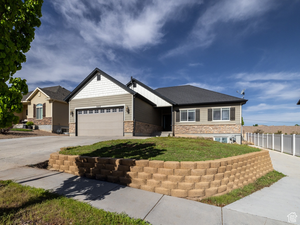 View of front of property featuring concrete driveway, an attached garage, and stone siding