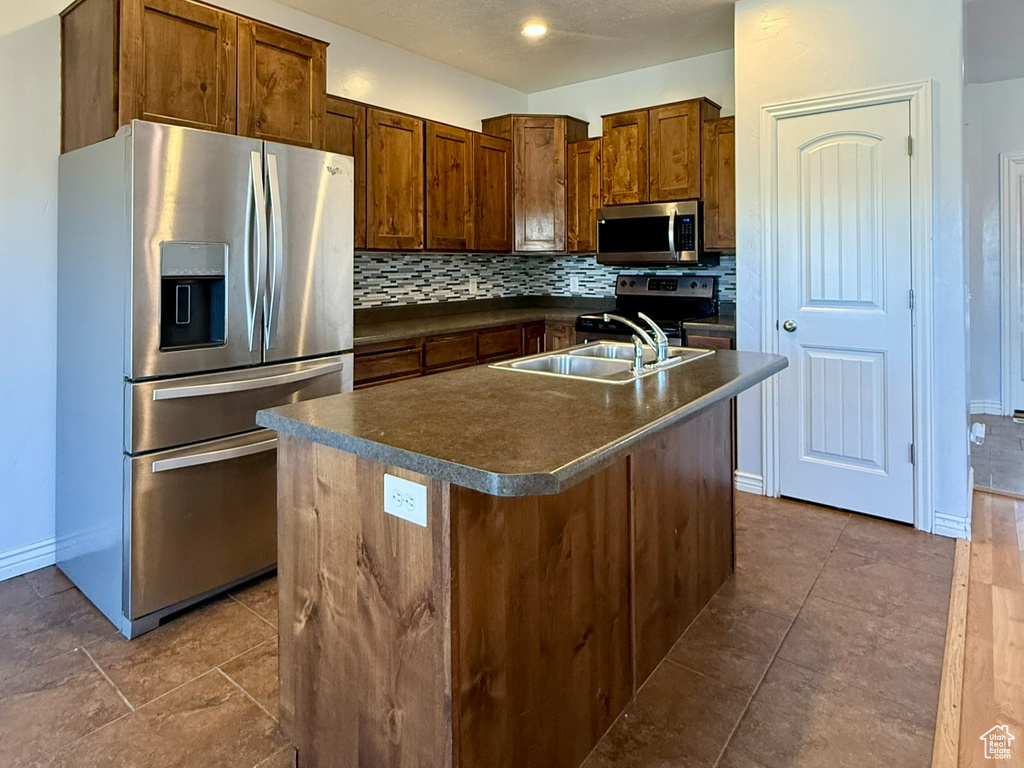 Kitchen featuring appliances with stainless steel finishes, dark countertops, backsplash, baseboards, and a textured ceiling