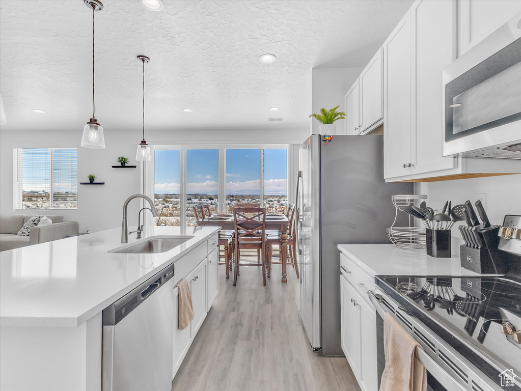 Kitchen with light countertops, appliances with stainless steel finishes, a sink, and white cabinetry