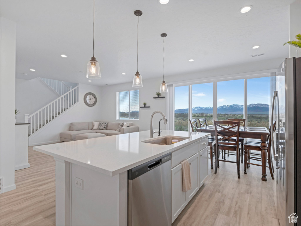 Kitchen featuring light wood-style flooring, white cabinetry, appliances with stainless steel finishes, a sink, and a mountain view