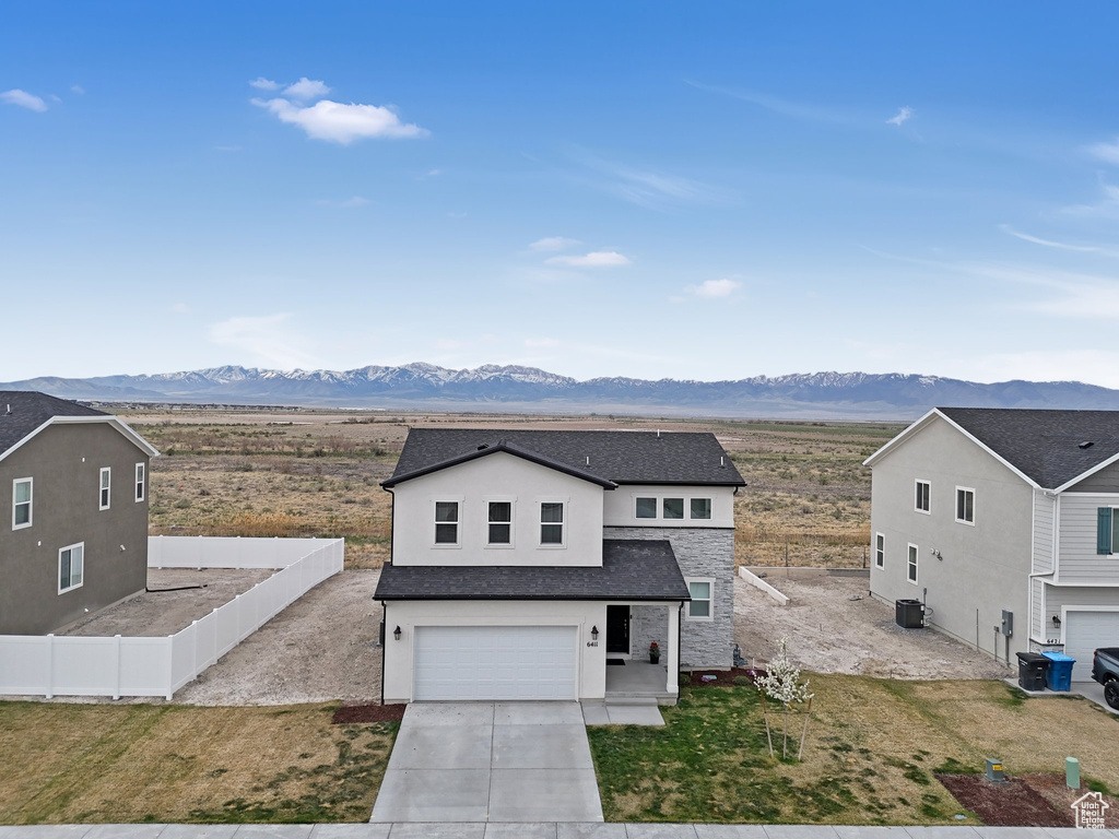 View of front of house featuring concrete driveway, stucco siding, a mountain view, an attached garage, and fence