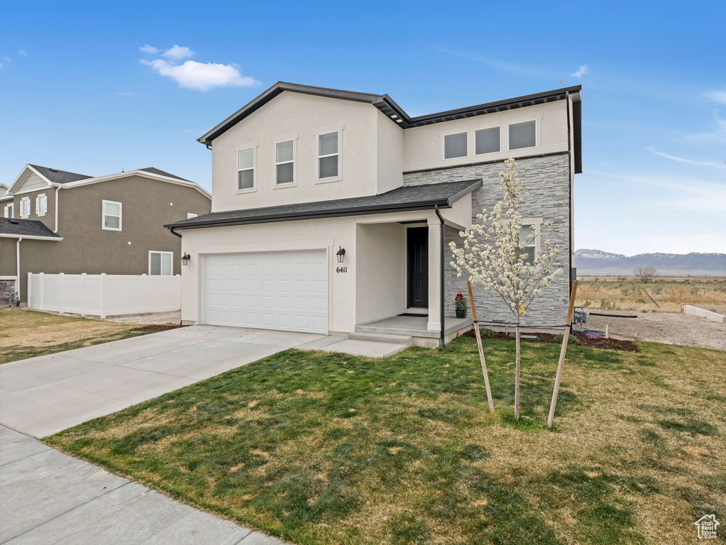 Traditional home with concrete driveway, an attached garage, fence, and stucco siding