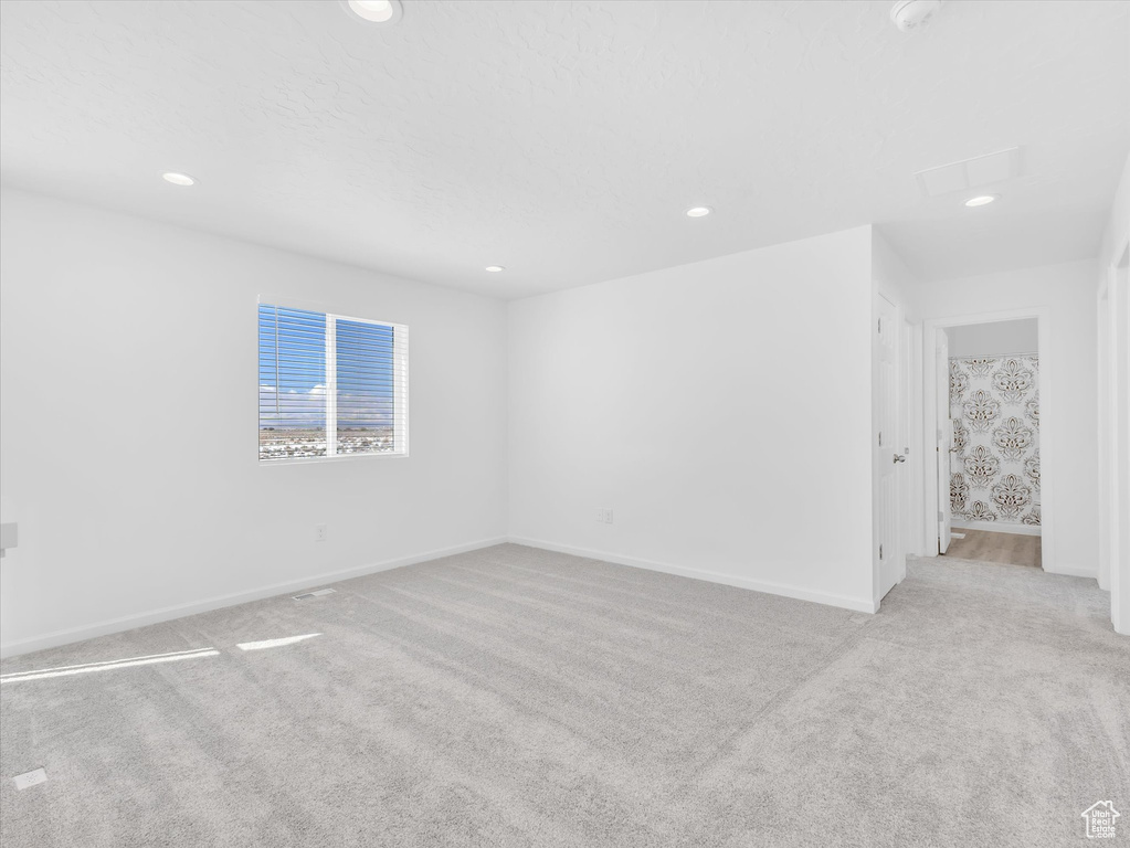 Unfurnished room with light carpet, baseboards, and recessed lighting