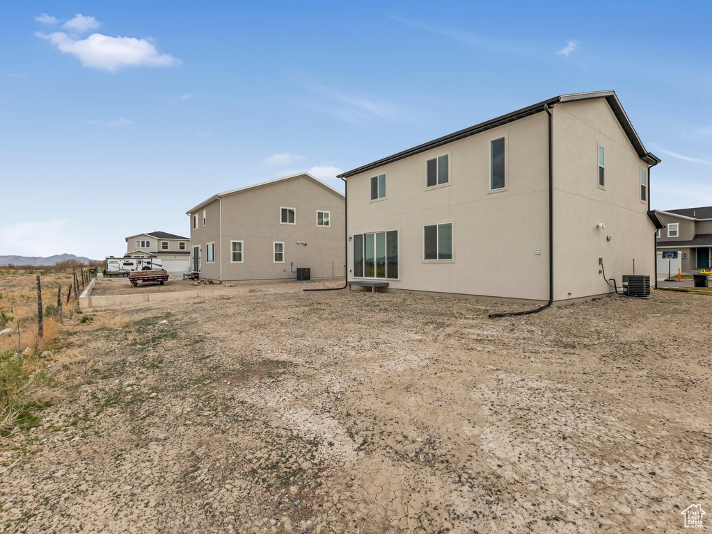 Rear view of property featuring central AC unit, stucco siding, and fence